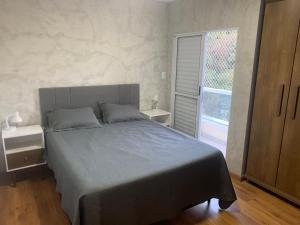 a bedroom with a large bed and a large window at Apto térreo novo 3 dorm - próximo ao centro in Poços de Caldas