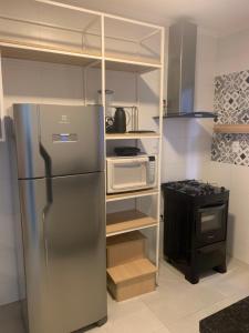 a kitchen with a stainless steel refrigerator and a microwave at Apto térreo novo 3 dorm - próximo ao centro in Poços de Caldas