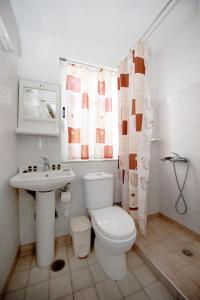 a white bathroom with a toilet and a sink at Maria Studios & Apartments in Kremasti