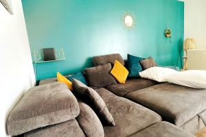 - un salon avec un canapé brun et un mur bleu dans l'établissement Penthouse de standing: Vue paris- 10min de l'aéroport Orly - Parking gratuit, à Orly