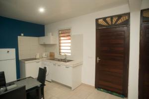 une petite cuisine avec un évier et une porte. dans l'établissement Maison de l'ébène Pas, à Cayenne