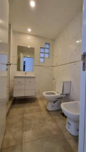 La salle de bains blanche est pourvue de toilettes et d'un lavabo. dans l'établissement Departamento Rivadavia, à Olavarría
