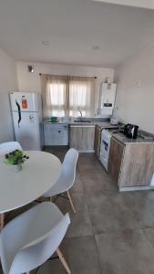Il comprend une cuisine équipée d'une table blanche et d'un réfrigérateur blanc. dans l'établissement Departamento Rivadavia, à Olavarría