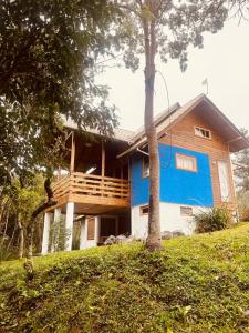 ein blau-weißes Haus mit Bäumen davor in der Unterkunft Casa Violeta in Urubici