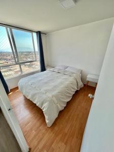 a bed in a room with a large window at Departamento Cómodo y Luminoso in Santiago