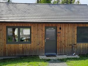 een houten gebouw met een deur en een raam bij Cosy chalet near Durbuy in nature in Somme-Leuze