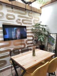 mesa de madera con sillas y TV en la pared en Loft céntrico con diseño único, en Tulancingo