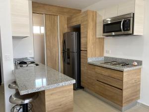 a kitchen with a refrigerator and a counter top at Nuevo Departamento con Excelente Ubicación y Muy Bonita Alberca - Residencial Almarena II in Mazatlán