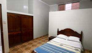 1 dormitorio con 1 cama con cabecero de madera y ventana en Hostal Las Palmeras, en Jaén