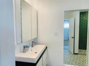 a white bathroom with a sink and a mirror at Modern + Midcentury House in B Bar H Ranch in Desert Hot Springs