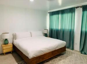 um quarto com uma cama grande e cortinas verdes em Modern + Midcentury House in B Bar H Ranch em Desert Hot Springs