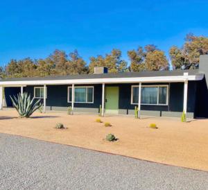 uma casa azul e verde com árvores ao fundo em Modern + Midcentury House in B Bar H Ranch em Desert Hot Springs