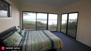 a bedroom with a bed and a view of the ocean at Bermagui bliss beachfront holiday house in Bermagui