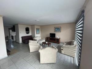 a living room with white couches and a tv at Tradición in Santa Cruz de la Sierra