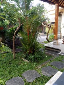 a garden with a palm tree and some rocks at Uma Pejeng in Ubud