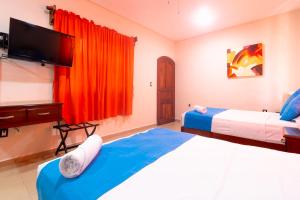 a bedroom with two beds and a flat screen tv at Hotel Bacalar Magico in Bacalar