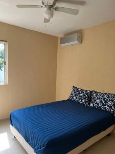 1 dormitorio con 1 cama azul y ventilador de techo en Tranquilidad y comodidad para ti, en Cancún
