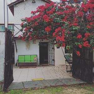 a house with red flowers on the front of it at Chalé do Coqueiro in Luis Correia