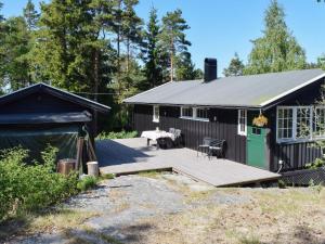 ein schwarzes Cottage mit einer Terrasse und einer grünen Tür in der Unterkunft Holiday home Halden IV in Halden