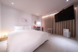 een slaapkamer met een wit bed en een flatscreen-tv bij Croissant Hotel Guri by ANNK in Guri