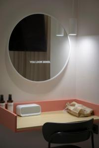 uno specchio su una parete sopra una scrivania con sedia di Croissant Hotel Guri by Aank a Guri