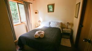 a bedroom with a bed with two slippers on it at Nutley Cottage with river view Bermagui Linen provided in Bermagui +5 photos