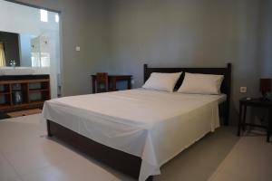 a bedroom with a large white bed and a bathroom at Rasti 2 homestay in Kuta Lombok