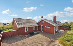 ein rotes Haus mit einer großen Terrasse davor in der Unterkunft Cozy Home In Hvide Sande With Kitchen in Hvide Sande