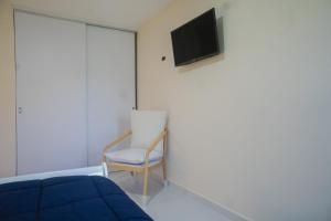 a bedroom with a bed and a chair and a tv at Pavia's Centerpoint Oasis in Oranjestad