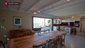 een grote houten tafel in een keuken met een groot raam bij Ocean Pearl Luxury beachfront Bermagui Linen provided in Bermagui