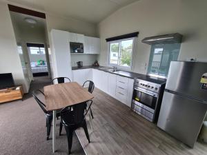 een keuken met een tafel, een fornuis en een koelkast bij Whakatane Holiday Park in Whakatane