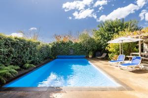 a swimming pool with two chairs and an umbrella at Village Apartment Havelock North in Havelock North