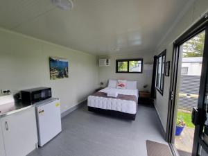 Whakatane Holiday Park في واكتاين: غرفة نوم صغيرة بها سرير وثلاجة