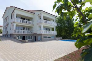 a house with a swimming pool in front of it at Apartments Gorančica in Malinska