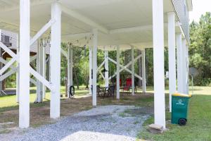 eine weiße Veranda mit weißen Säulen und einem Mülleimer in der Unterkunft Cozy cottage surrounded by fun in Pass Christian