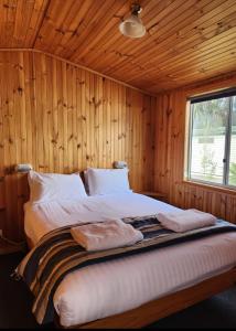 a bedroom with a bed in a wooden cabin at Strahan Beach Tourist Park in Strahan