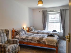 1 dormitorio con 2 camas, silla y ventana en Constable Cottage, en Brampton