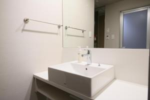 a white bathroom with a sink and a mirror at Hotel Gracery Shinjuku in Tokyo