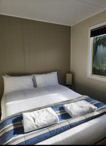 a bedroom with a bed with two pillows on it at Strahan Beach Tourist Park in Strahan