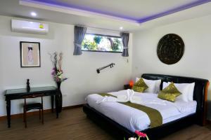 a bedroom with a bed and a table and a window at Jasmine Village in Rawai Beach