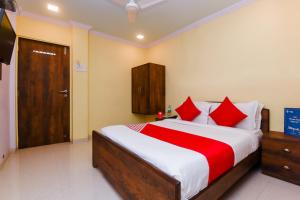 a bedroom with a large bed with red pillows at OYO Hotel Stayland Near Juhu Beach in Mumbai
