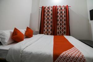 a bed with orange and white pillows in a room at Jp Homes in Kamakhya