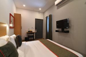een slaapkamer met een bed en een flatscreen-tv bij Townhouse Royapettah Near U.S Consulate in Chennai