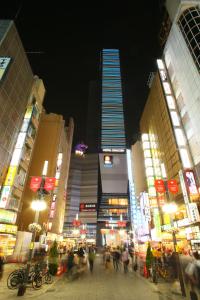 a busy city street at night with a tall building at Hotel Gracery Shinjuku in Tokyo