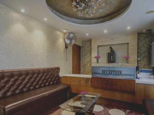 a waiting room with a brown leather couch and a reception at Collection O THE CROWN HOTEL in Hyderabad