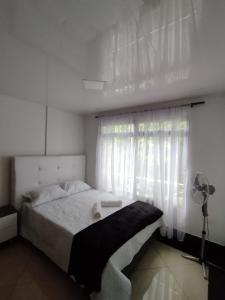 a white bedroom with a bed and a window at Apartamentos Florida Nueva estadio in Medellín