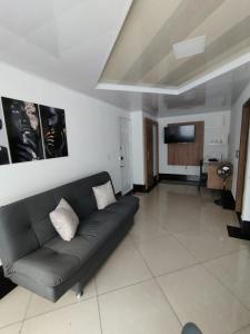 een woonkamer met een zwarte bank en een tv bij Apartamentos Florida Nueva estadio in Medellín
