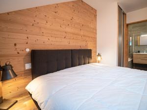 - une chambre avec un grand lit et un mur en bois dans l'établissement Appartement Valmorel, 3 pièces, 7 personnes - FR-1-356-415, à Valmorel