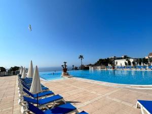 - une piscine avec des chaises bleues et blanches et l'océan dans l'établissement Appartement Cannes la Bocca, 3 pièces, 6 personnes - FR-1-609-76, à Cannes