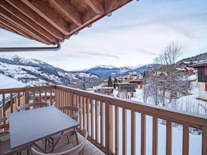 d'un balcon avec une table, des chaises et des montagnes enneigées. dans l'établissement Appartement Valmorel, 3 pièces, 7 personnes - FR-1-356-410, à Valmorel